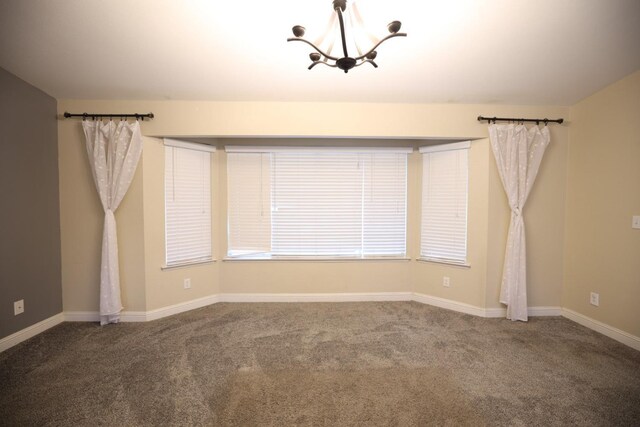 empty room featuring carpet and a notable chandelier