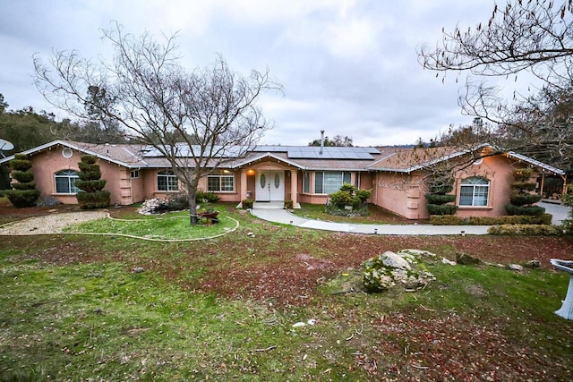 single story home with a front yard and solar panels