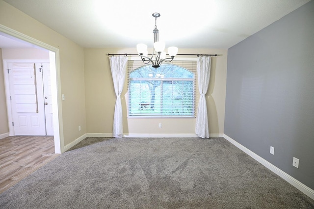 carpeted spare room featuring a notable chandelier