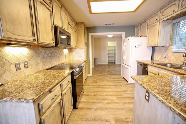 kitchen with light stone countertops, sink, light hardwood / wood-style flooring, light brown cabinetry, and appliances with stainless steel finishes