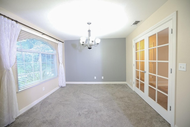 empty room with light colored carpet and an inviting chandelier