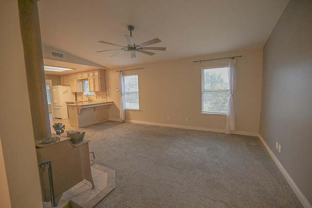 unfurnished living room featuring a healthy amount of sunlight, light colored carpet, ceiling fan, and lofted ceiling