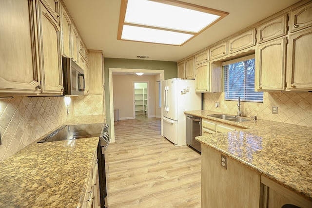 kitchen featuring light stone countertops, stainless steel appliances, sink, light brown cabinets, and light hardwood / wood-style flooring