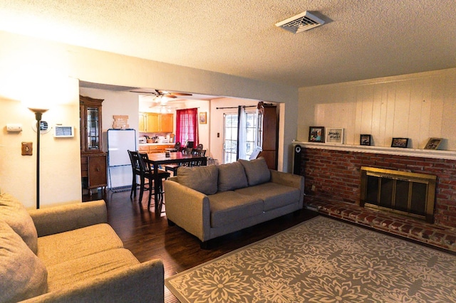 living room featuring ceiling fan, dark hardwood / wood-style floors, a brick fireplace, and a textured ceiling