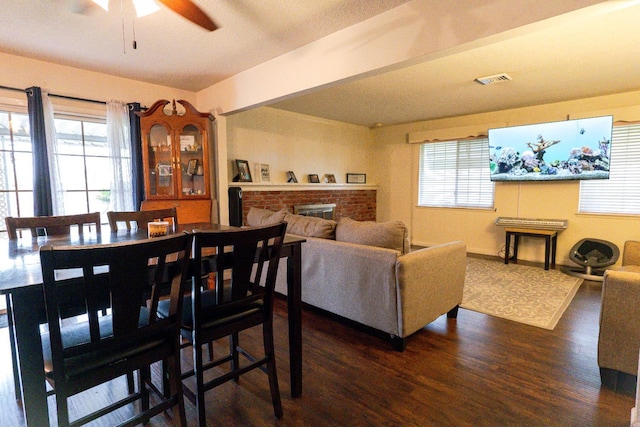 dining space with a wealth of natural light, ceiling fan, dark hardwood / wood-style floors, and a fireplace