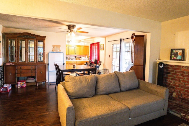 living room with ceiling fan, dark wood-type flooring, and a textured ceiling