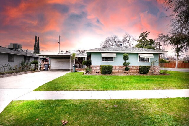 ranch-style home with a garage and a yard