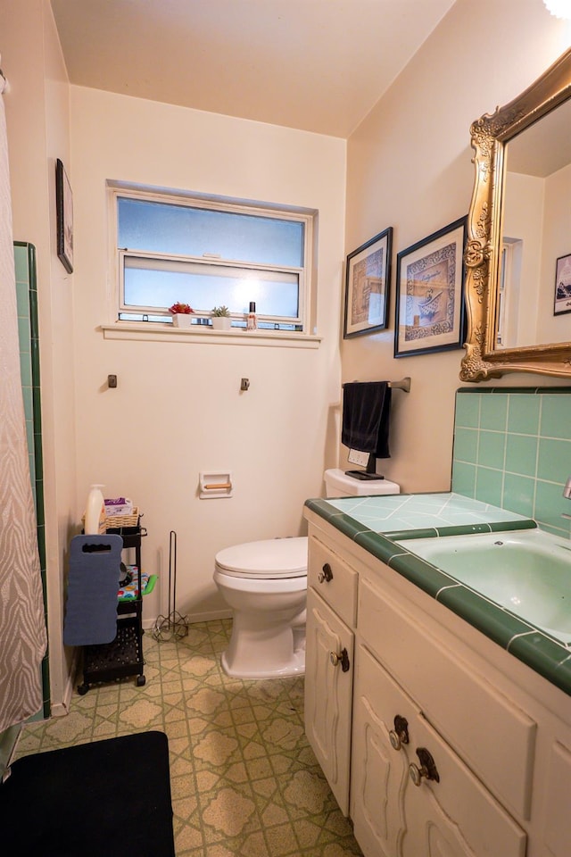 bathroom with vanity, toilet, and decorative backsplash