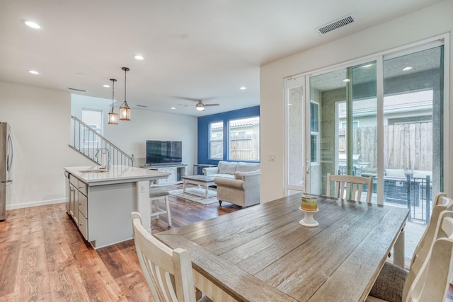 dining space featuring light hardwood / wood-style flooring, ceiling fan, and sink