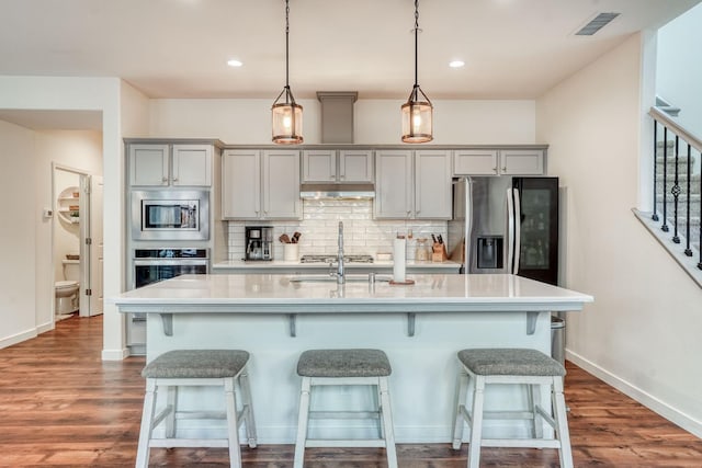 kitchen featuring appliances with stainless steel finishes, gray cabinets, and a center island with sink