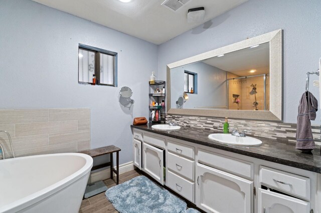 bathroom with decorative backsplash, vanity, hardwood / wood-style flooring, and plus walk in shower