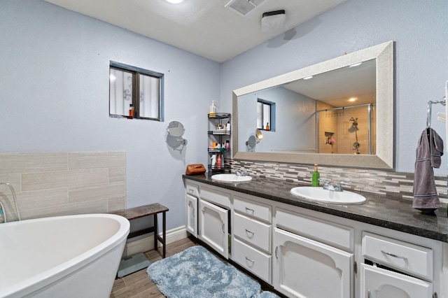 full bath featuring wood finished floors, backsplash, a sink, and a stall shower