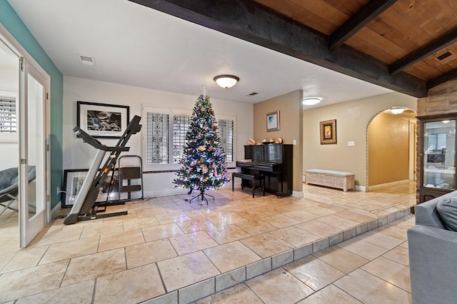 workout area featuring arched walkways, a wealth of natural light, wooden ceiling, and visible vents