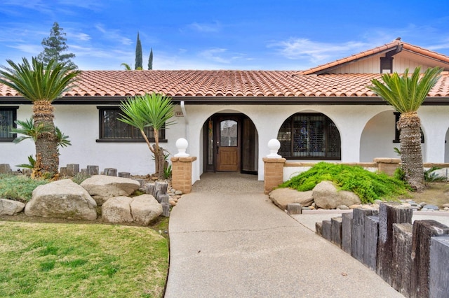 mediterranean / spanish-style house featuring covered porch, a tiled roof, and stucco siding