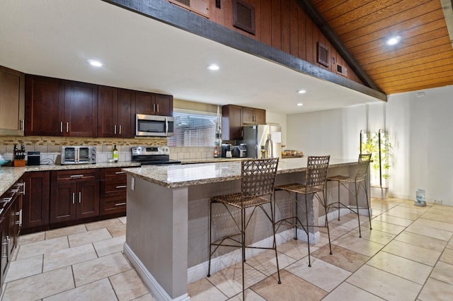 kitchen with visible vents, a kitchen breakfast bar, appliances with stainless steel finishes, light stone countertops, and tasteful backsplash