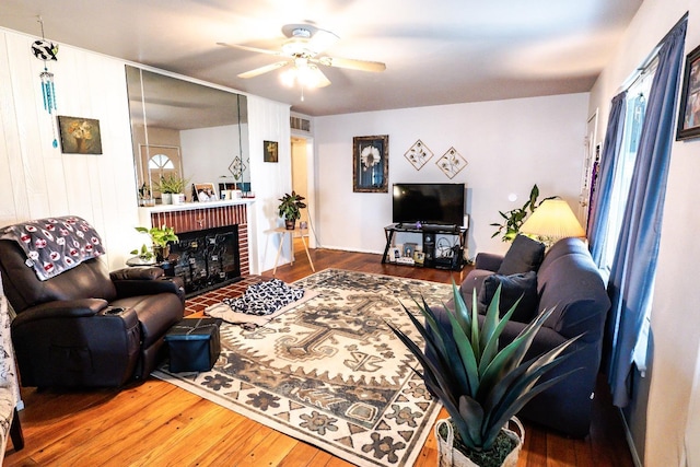 living room featuring a fireplace, hardwood / wood-style flooring, and ceiling fan