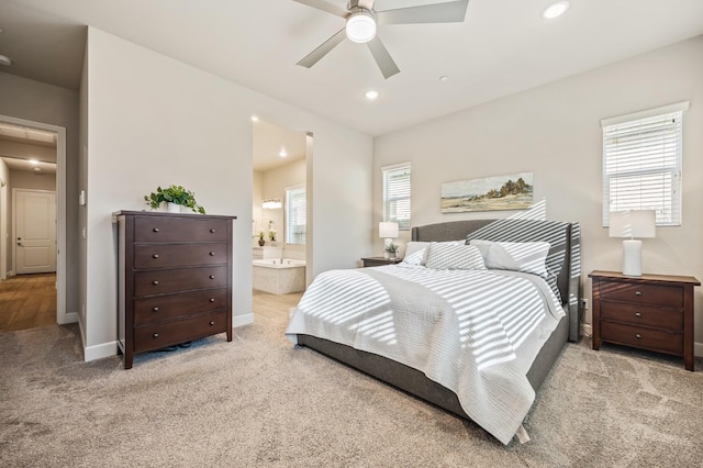 bedroom featuring ensuite bath, ceiling fan, light colored carpet, and multiple windows