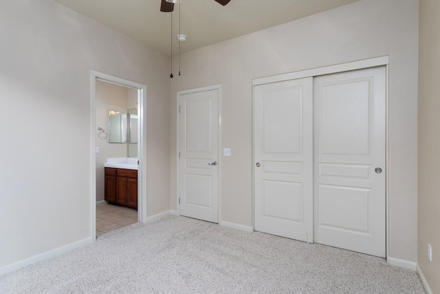 unfurnished bedroom with ensuite bath, light carpet, a closet, and ceiling fan