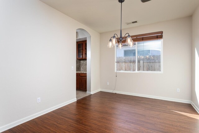 empty room featuring dark hardwood / wood-style flooring and an inviting chandelier