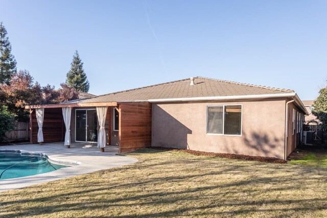 back of house featuring a lawn, a patio area, a fenced in pool, and central AC