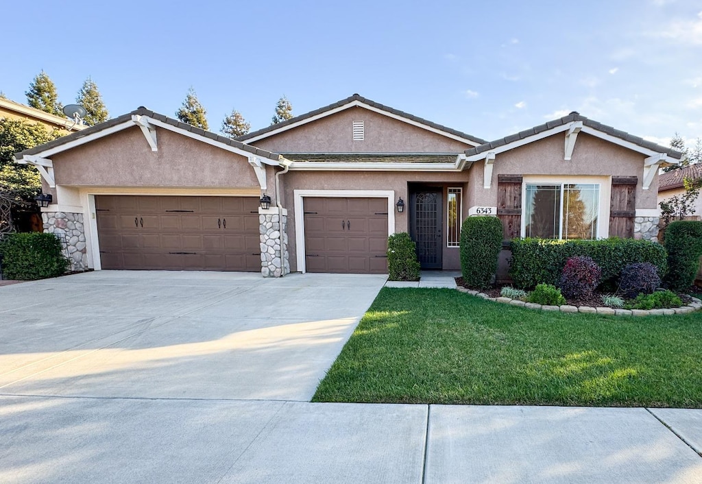 6343 W Babcock Ct, Visalia, CA 93291 - single story home with stucco siding, a garage, stone siding, a front yard, and driveway