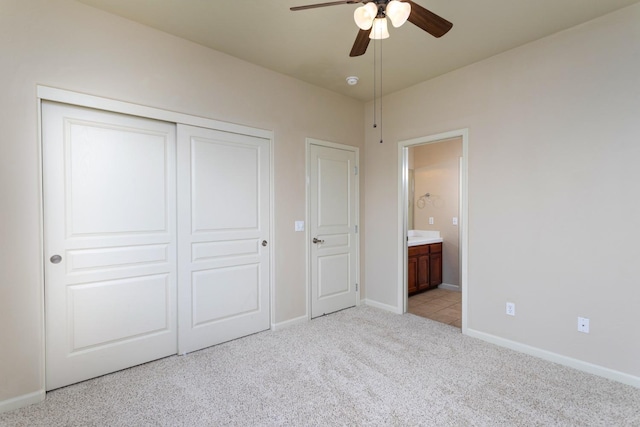 unfurnished bedroom featuring ceiling fan, a closet, light carpet, and ensuite bath