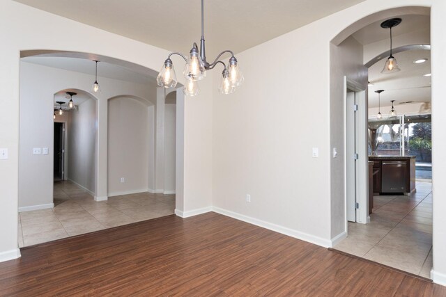 spare room with hardwood / wood-style flooring and a notable chandelier