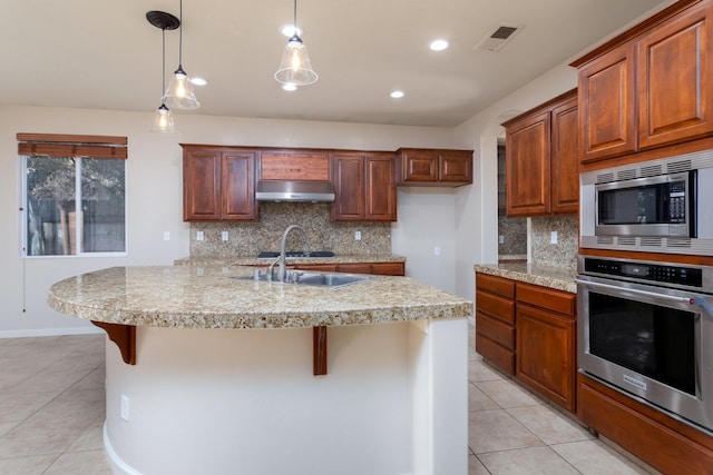 kitchen with a kitchen bar, light tile patterned floors, appliances with stainless steel finishes, and tasteful backsplash