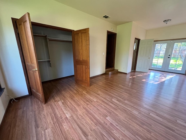 unfurnished bedroom with a closet, french doors, and hardwood / wood-style floors