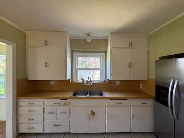 kitchen with white cabinetry, stainless steel fridge, sink, and light tile patterned flooring