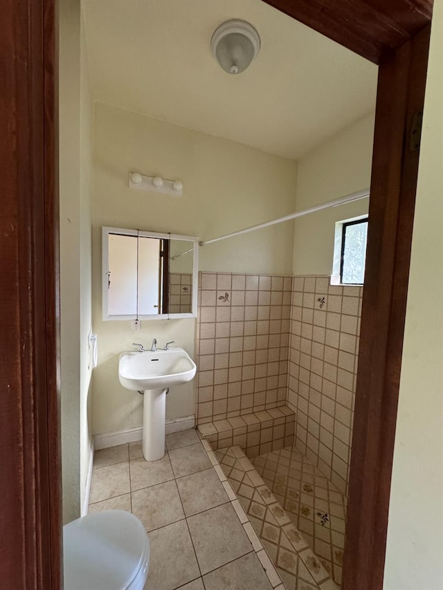 bathroom featuring tile patterned flooring, a shower, toilet, and tile walls