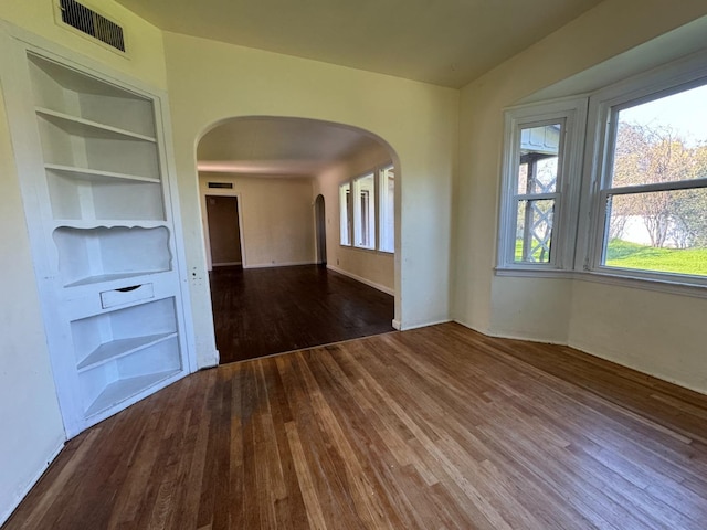 empty room featuring built in features and dark wood-type flooring