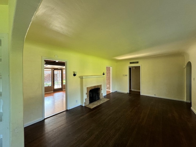 unfurnished living room with dark wood-type flooring and a tiled fireplace