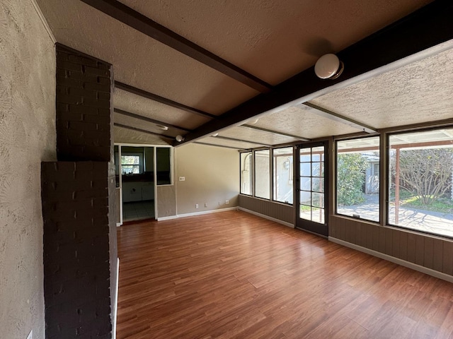 unfurnished sunroom featuring vaulted ceiling with beams