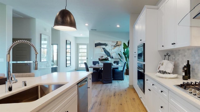 kitchen with sink, tasteful backsplash, decorative light fixtures, white cabinets, and appliances with stainless steel finishes