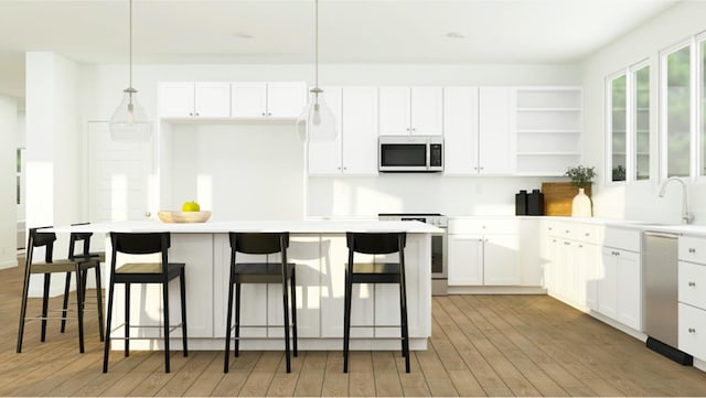 kitchen with white cabinetry, sink, pendant lighting, a kitchen bar, and appliances with stainless steel finishes