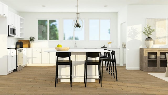 kitchen featuring pendant lighting, white cabinets, light hardwood / wood-style flooring, a kitchen bar, and range