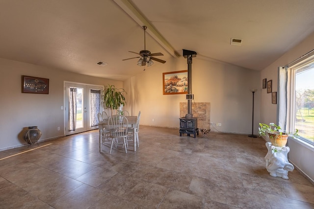 unfurnished dining area with a wood stove, lofted ceiling with beams, visible vents, and french doors