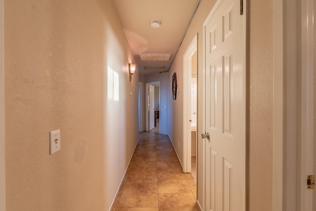 hall with light tile patterned flooring, visible vents, and baseboards