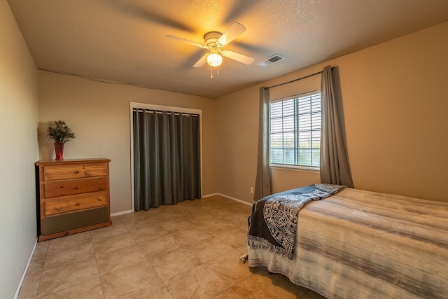 bedroom featuring light tile patterned floors, visible vents, ceiling fan, a textured ceiling, and baseboards