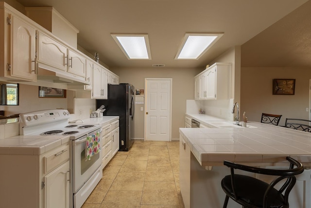 kitchen featuring tile countertops, a peninsula, a sink, white range with electric stovetop, and a kitchen bar