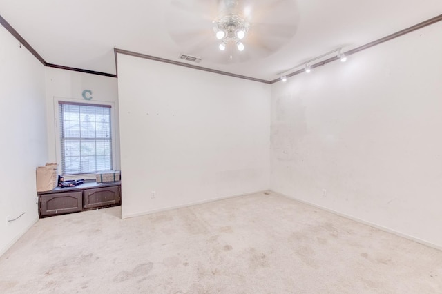 empty room with track lighting, ceiling fan, crown molding, and light colored carpet