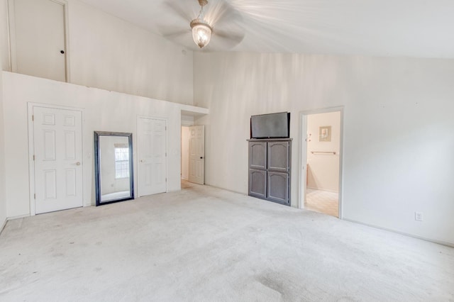 interior space featuring ceiling fan, light carpet, and a high ceiling