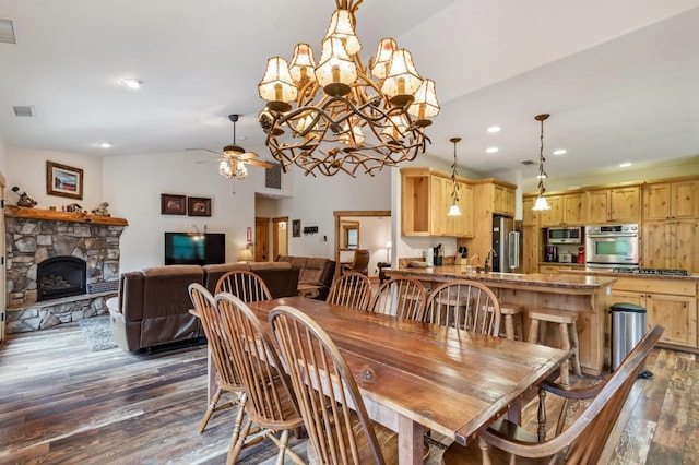 dining area with a fireplace, ceiling fan with notable chandelier, dark hardwood / wood-style floors, and lofted ceiling