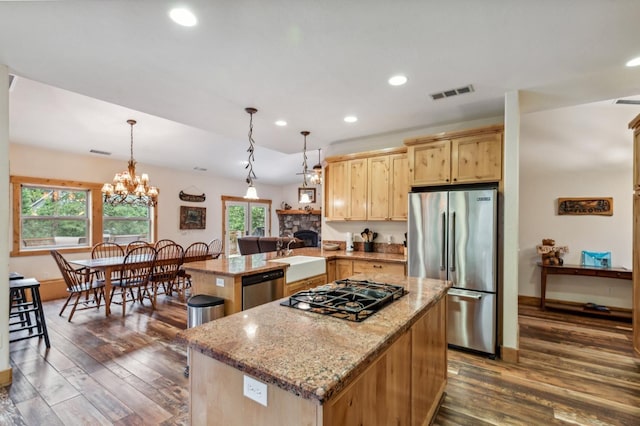 kitchen with kitchen peninsula, appliances with stainless steel finishes, sink, a chandelier, and a center island