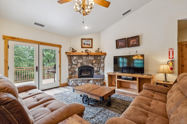 living room with ceiling fan, french doors, light hardwood / wood-style floors, vaulted ceiling, and a fireplace