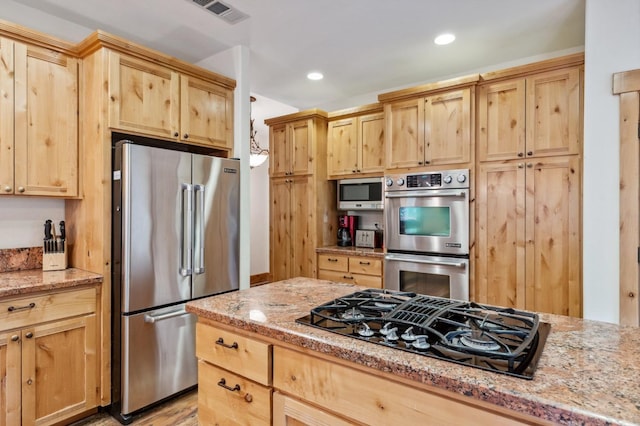 kitchen featuring light brown cabinets, light stone counters, and appliances with stainless steel finishes