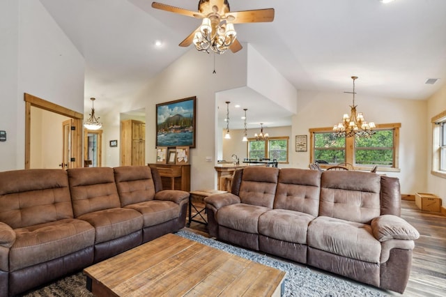 living room featuring hardwood / wood-style floors, high vaulted ceiling, and ceiling fan with notable chandelier