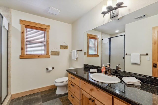 bathroom with vanity, toilet, a shower with door, and a wealth of natural light