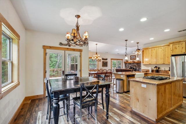 kitchen with stainless steel appliances, pendant lighting, light brown cabinets, dark hardwood / wood-style floors, and a kitchen island